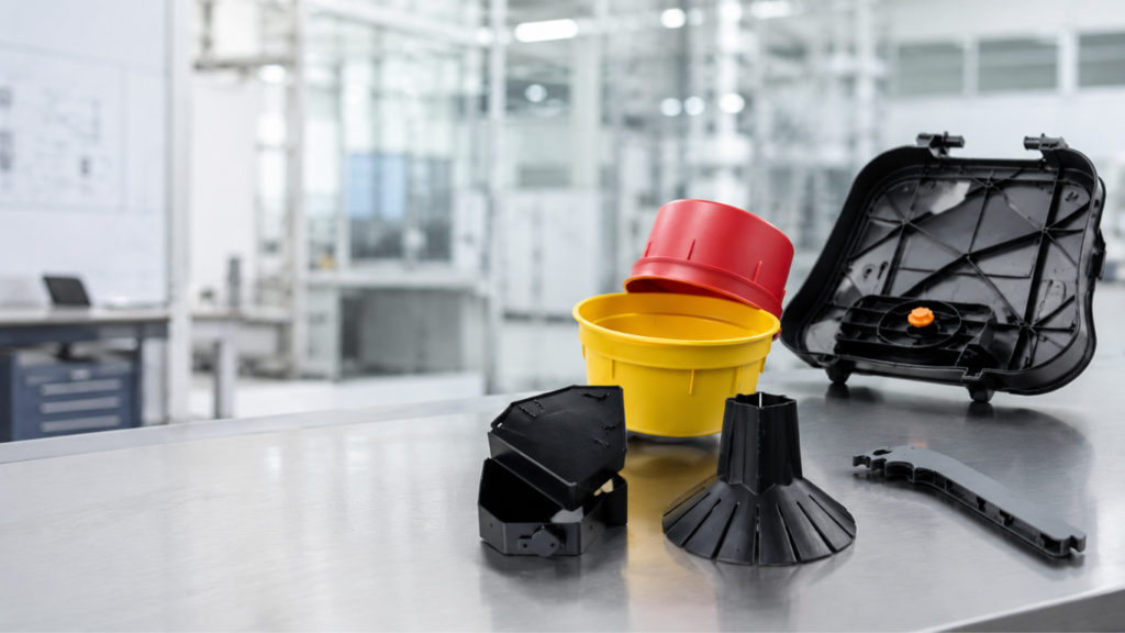 Seau jaune, couvercle rouge et carters noirs en plastique posés sur un plan de travail.