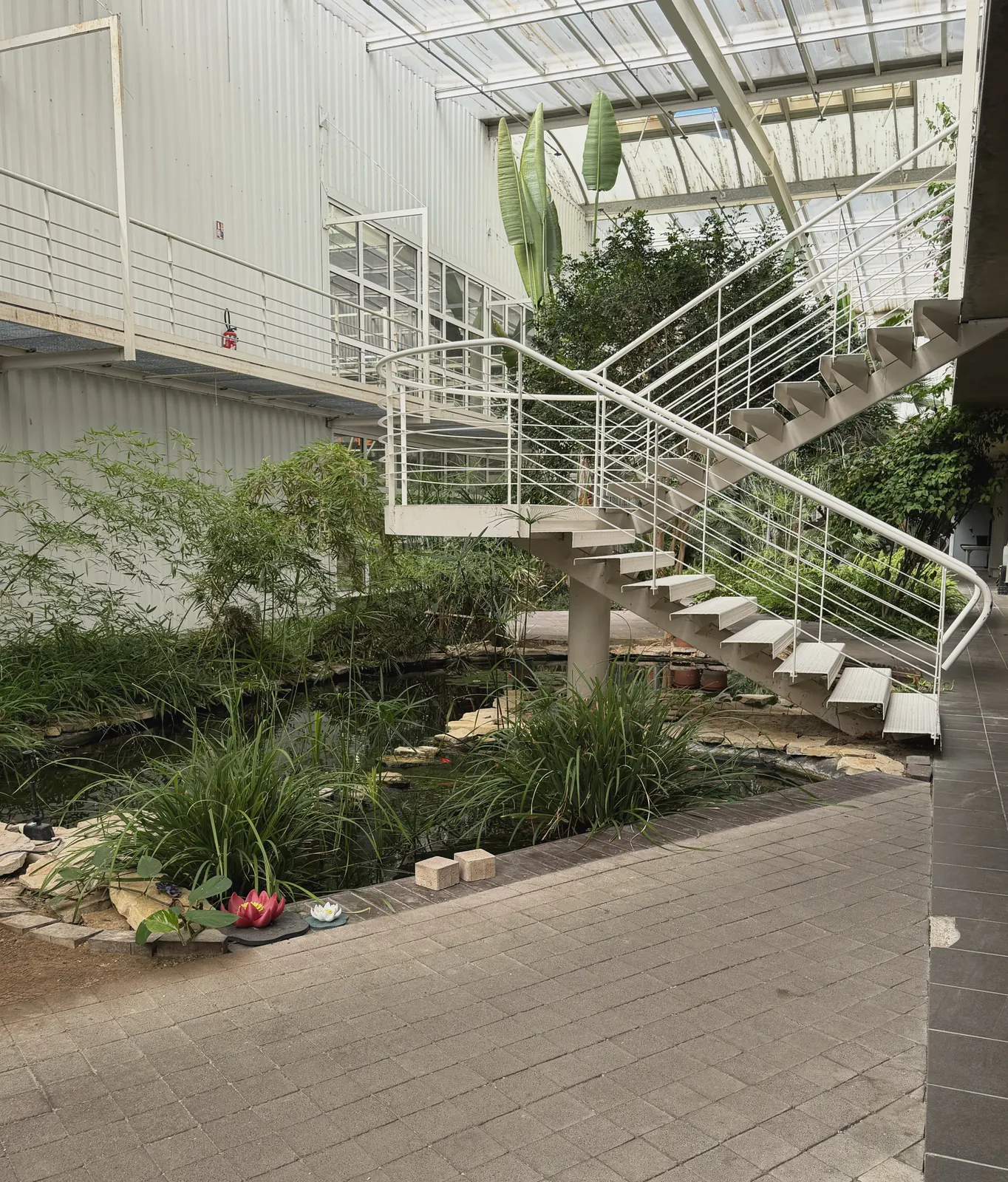 Atrium végétalisé du site Plazur Industries : escalier métallique et bassin intérieur.