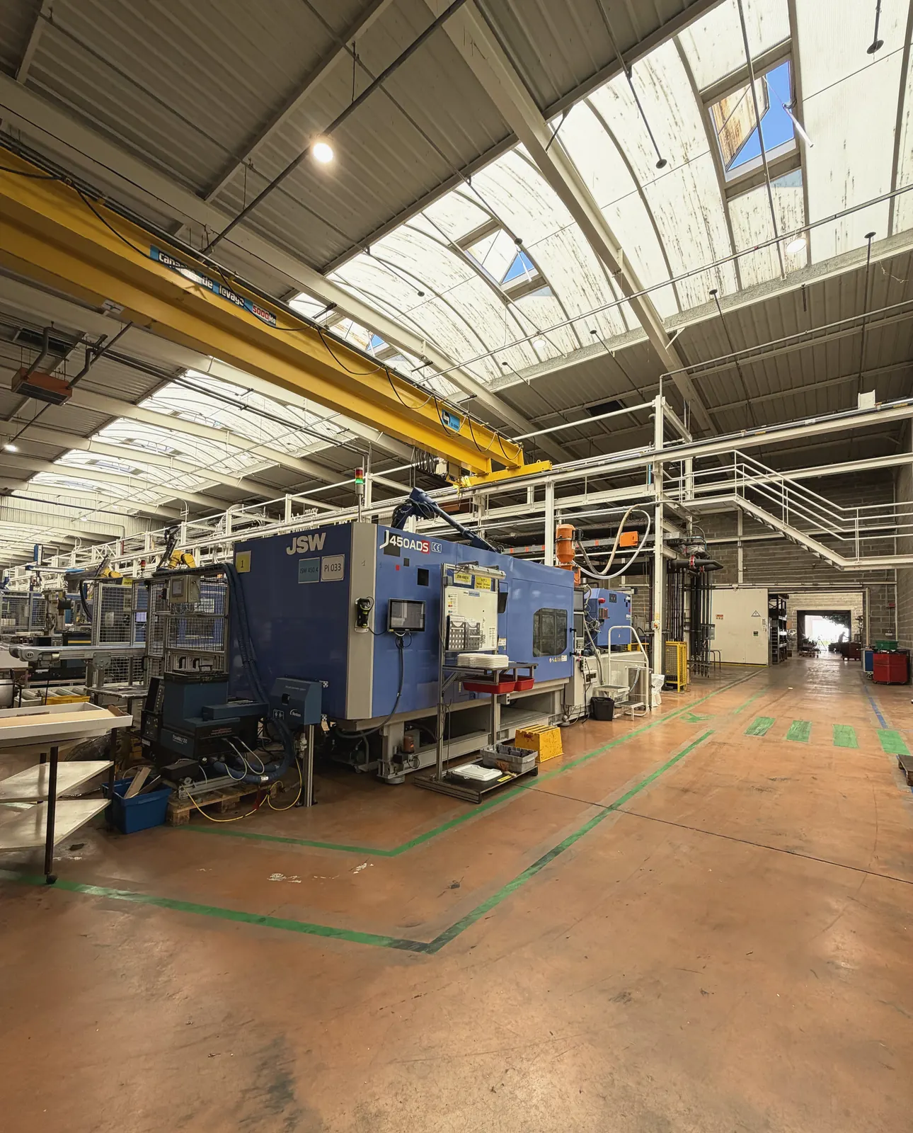 Presse à injecter et pont roulant dans l'atelier de production de Plazur Industries.
