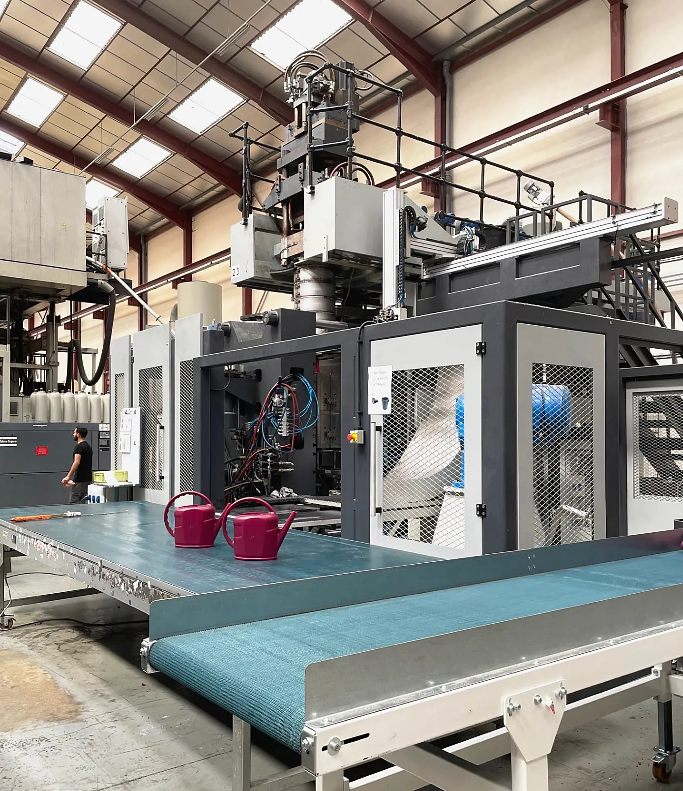 Machine d'extrusion-soufflage et convoyeur de sortie dans l'atelier Plazur Industries.
